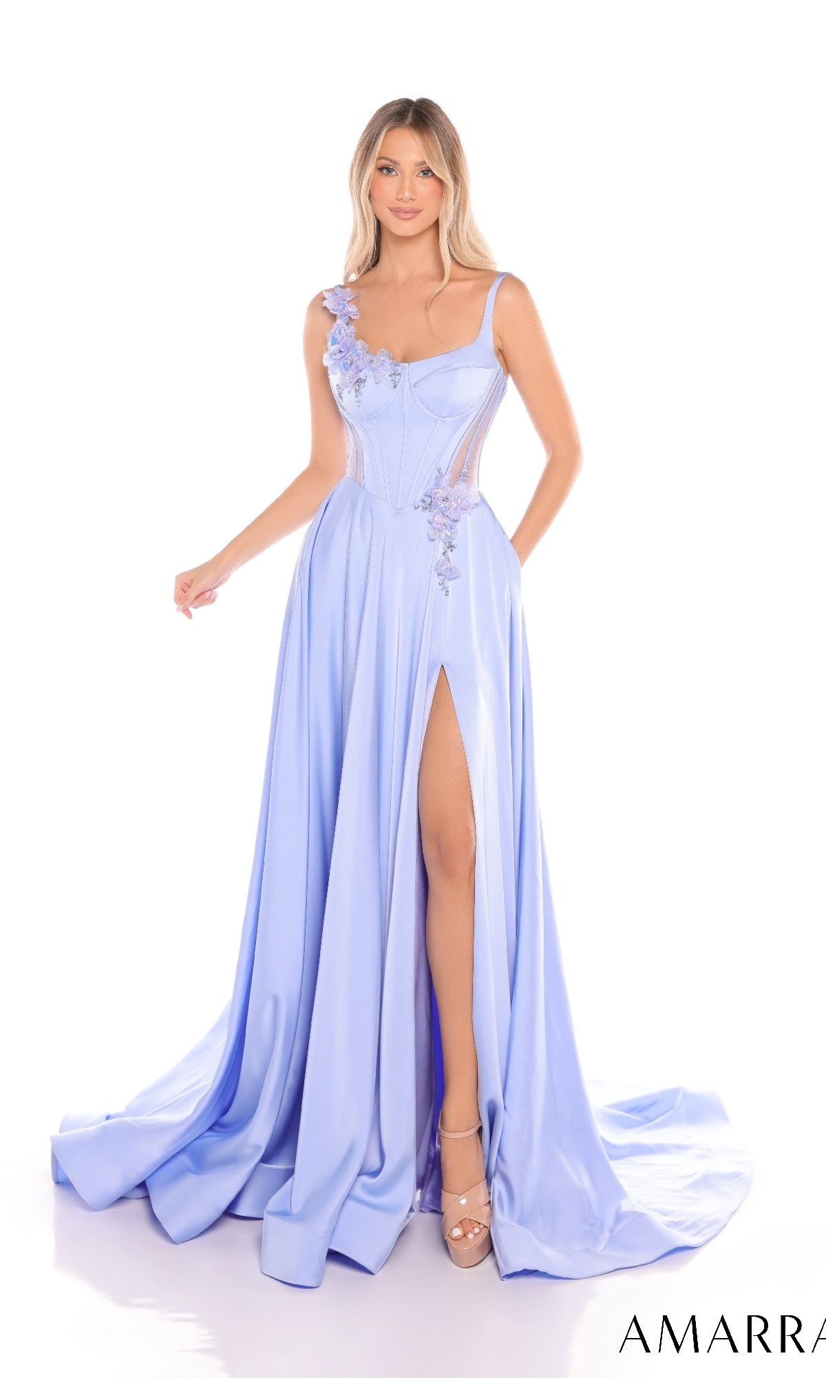 A woman stands against a white background wearing the Amarra 88214 Long Prom Dress in light blue, featuring floral applique, a corset bodice, sheer panels, and a high leg slit.